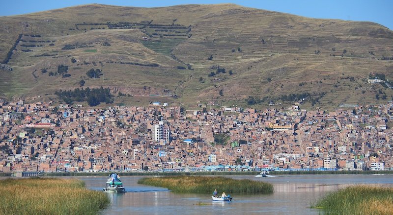 Puno city and mountain views fro our boat leaving Lake Titicaca tour 