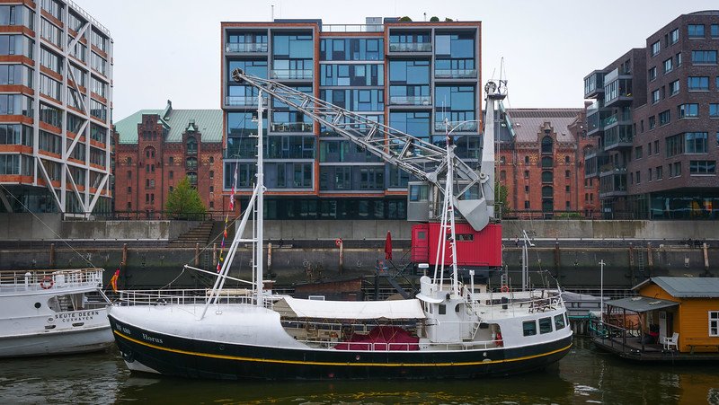 Red-brick warehouses and modern glass buildings line the canals in Hamburg's Speicherstadt neighbourhood with boats docked nearby Red-brick warehouses and modern glass buildings line the canals in Hamburg's Speicherstadt neighbourhood with boats docked nearby