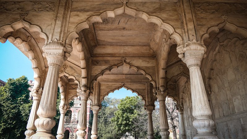 Detailed marble arches and carved pillars showcasing Mughal architecture inside the Red Fort in Delhi, India