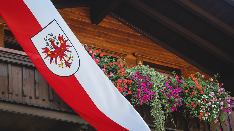 Reith im Alpbachtal during the Almabtrieb with Austrian flag and banner next to gorgeous and colorful flowerpots in Austria