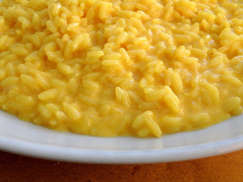 Close-up of creamy golden Risotto alla Milanese, a traditional saffron-infused rice dish from Milan, Italy, served on a white plate