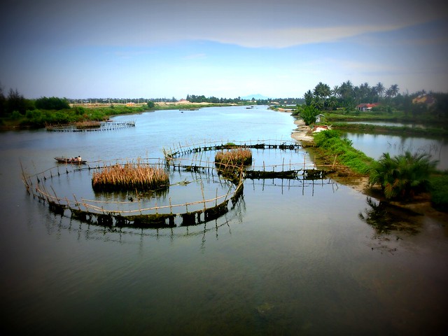 River near Tra Que, Vietnam with countryside views and a few fishing boats plying the waters 