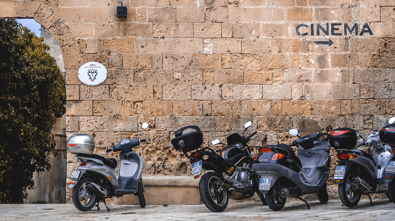 Row of scooters in Matera with a sign pointing to a cinema Row of scooters in Matera with a sign pointing to a cinema