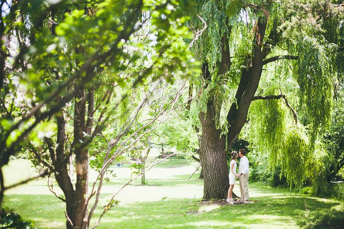 Romantic wedding portrait of Samuel and Audrey Jeffery standing together under a large willow tree, framed by lush summer greenery in Brampton, Ontario, capturing an intimate moment during their nature-inspired outdoor celebration