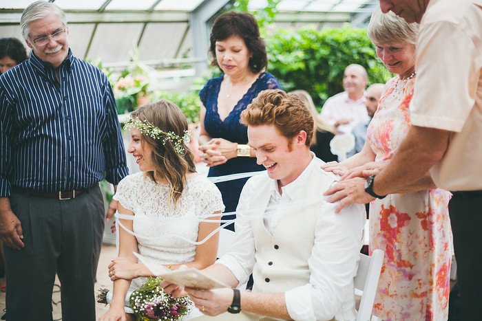 Samuel and Audrey getting married in Brampton, Ontario, surrounded by family and friends during their summer wedding ceremony. The bride smiles in a lace dress with a floral crown, while the groom laughs, creating a warm and intimate celebration scene