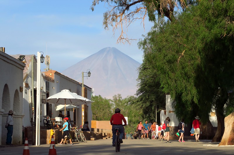 San Pedro de Atacama riding a bicycle in the market area with scenic mountain backdrop in Chile
