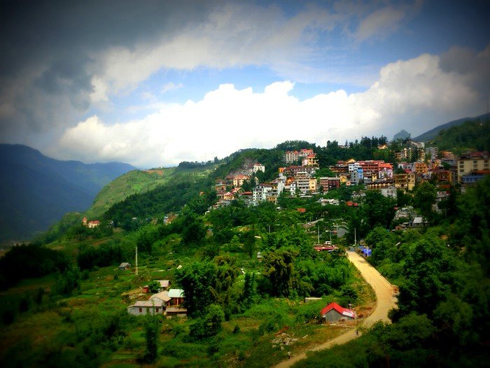 Colorful hillside town of Sapa nestled among lush green mountains and valleys under dramatic clouds in Vietnam