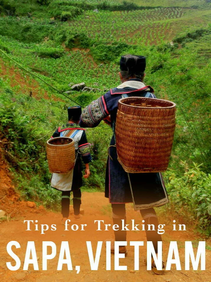 Two local women in traditional embroidered attire carrying woven baskets while trekking through lush green terraced hills near Sapa in northern Vietnam, with text overlay reading “Tips for Trekking in Sapa, Vietnam”