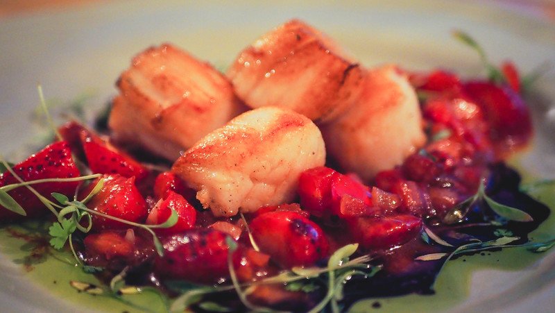 Seared scallops plated with a vibrant strawberry compote and microgreens at Auberge des Appalaches in Sutton, Quebec, showcasing the fine dining experience in the Eastern Townships