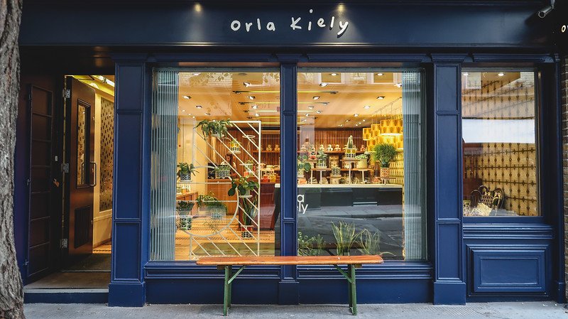 Exterior of the Orla Kiely shop in London’s Seven Dials, with navy storefront, large display windows, and a warm interior filled with designer homeware and fashion, inviting shoppers into this stylish boutique in the heart of the city