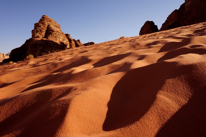 Shadows in the desert sand of Wadi Rum Jordan on a steep incline macro details from a low level perspective 