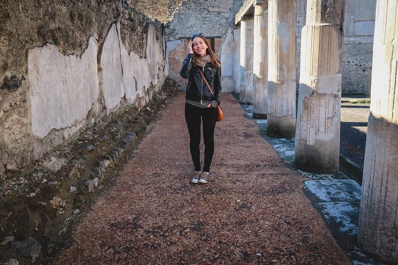 Should I stay in Pompei? Here we look at the pros and cons for those visiting Italy with That Backpacker Audrey Bergner posing at the ruins Should I stay in Pompei? Here we look at the pros and cons for those visiting Italy with That Backpacker Audrey Bergner posing at the ruins