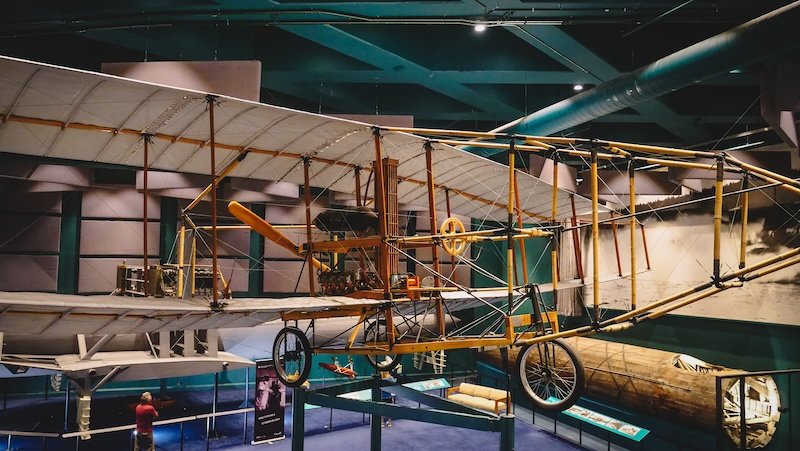 A historic Silver Dart aircraft replica is suspended from the ceiling inside the Alexander Graham Bell National Historic Site museum in Baddeck, Nova Scotia, showcasing Alexander Graham Bell’s pioneering aviation achievements along the Cabot Trail in Cape Breton