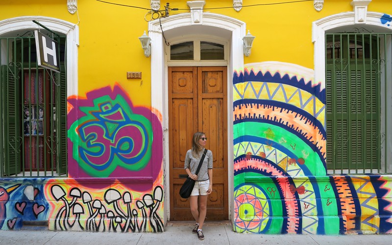 Street art and colorful buildings in Valparaiso, Chile with That Backpacker Audrey Bergner standing by a door for sense of scale 