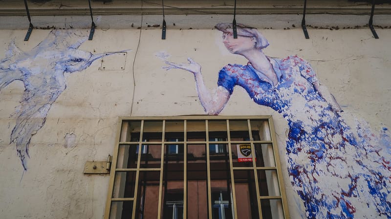 Street art in Kazimierz with a shuttered window and a women mural reaching out to a bird in Krakow, Poland Street art in Kazimierz with a shuttered window and a women mural reaching out to a bird in Krakow, Poland