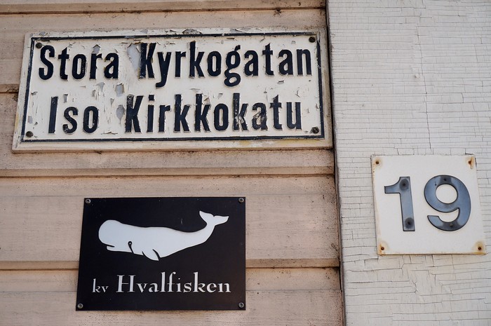 Street signs with images of sea creatures in Ekenäs, Finland saying Stora Kyrkogatan Iso Kirkkokatu 19 Hvalfisken