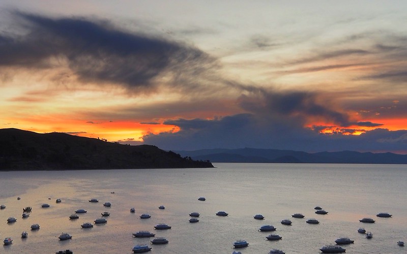 Sunset on Lake Titicaca, Copacabana, Bolivia with boats dotting the lake and gorgeous colors light the clouds on fire 