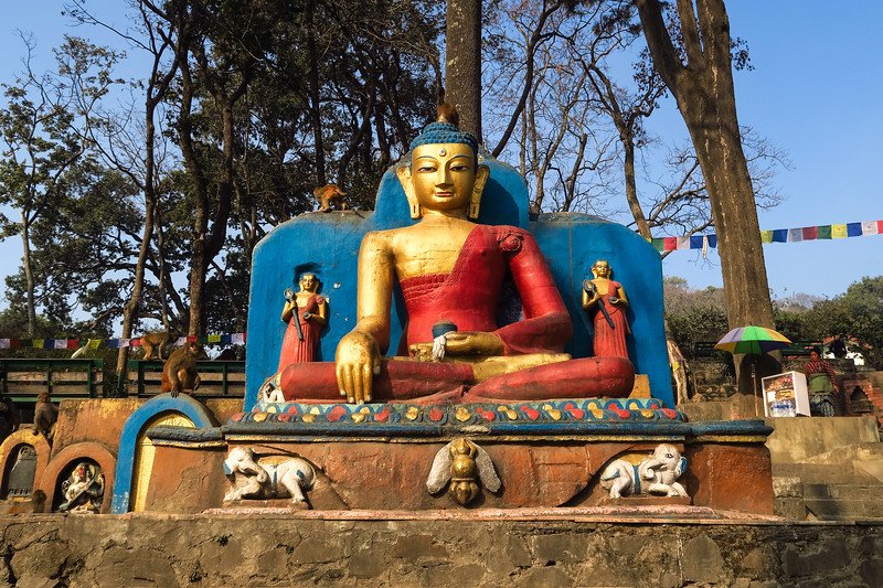 Golden Buddha statue at Swayambhunath, the Monkey Temple in Kathmandu, Nepal, surrounded by colorful prayer flags, stone carvings, and playful monkeys that highlight the city’s spiritual and cultural charm