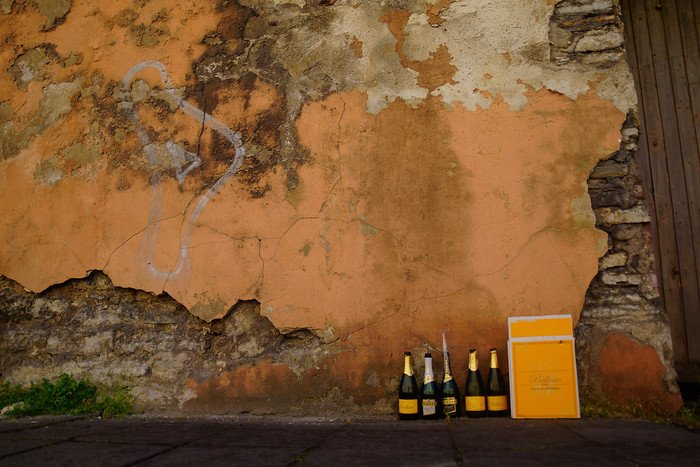 Empty champagne bottles lined against a crumbling old wall in Tallinn, Estonia, capturing the city’s street culture and contrasts on a day trip from Helsinki