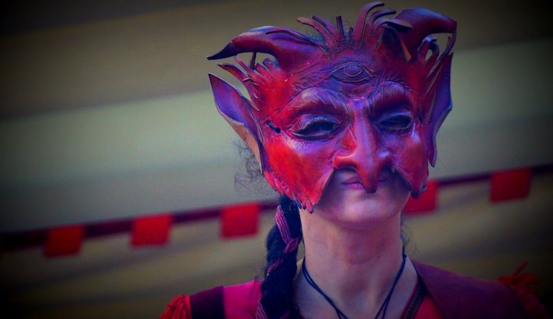 Performer in elaborate red devil mask during medieval street performance in Tallinn, Estonia on a day trip from Helsinki