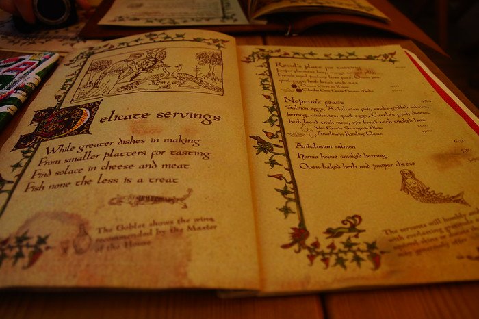 Medieval-style illustrated menu at Olde Hansa restaurant in Tallinn, Estonia, featuring ornate calligraphy and traditional food offerings