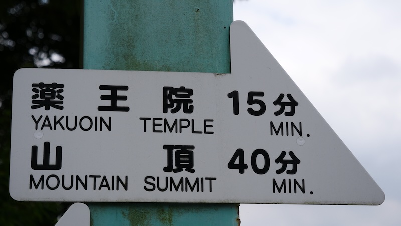 Temple and mountain summit signboard high atop mountain Takao, Japan 