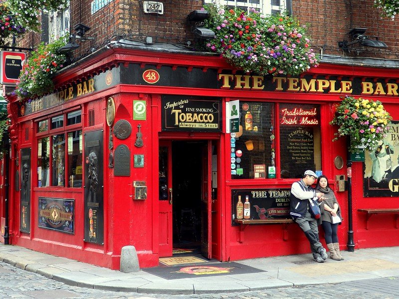 The Temple Bar pub in Dublin, Ireland with its bright red facade decorated with hanging flower displays