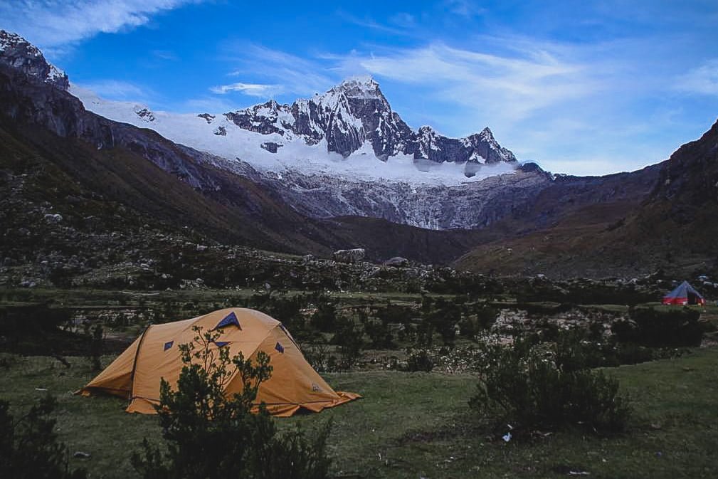 Tents at Taullipampa Camp with Taulliraju Mountain in the distance with stunning snow capped peaks off in the distance