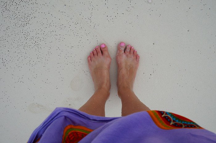 That Backpacker Audrey Bergner stands barefoot with pink-painted toenails in the gentle surf on soft white sand while walking along a tranquil beach in Cayo Santa María, Cuba during a relaxing tropical getaway