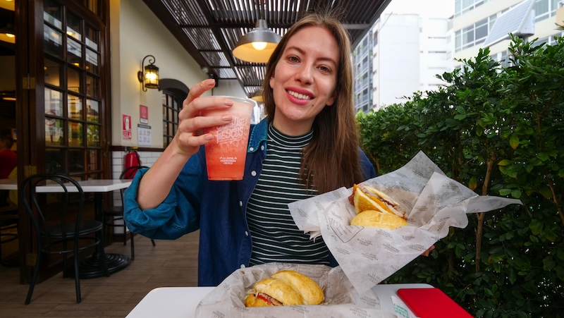 That Backpacker Audrey Bergner eating pan con chicharron sandwich as a street food snack in Miraflores, Lima, Peru 