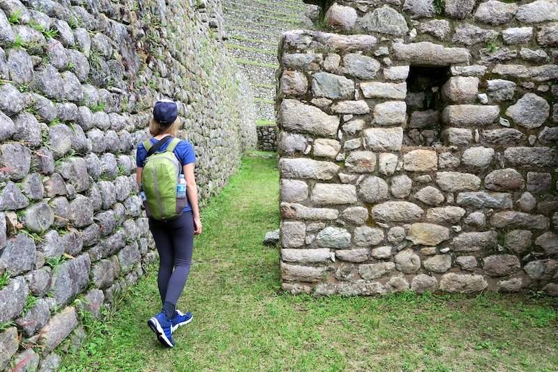 That Backpacker Audrey Bergner exploring Machu Picchu with a day pack and two waters along with layers and a baseball cap for sun protection in Peru backpacking South America 