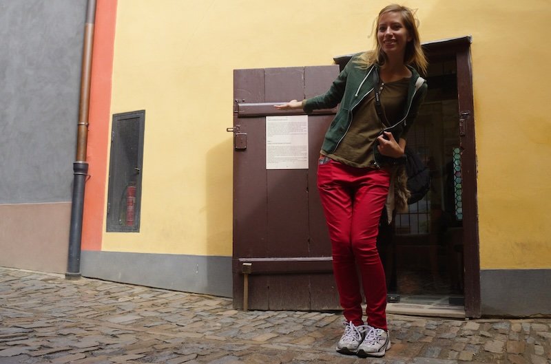 That Backpacker Audrey Bergner playfully posing beside a tiny historic doorway along the cobblestone Golden Lane inside Prague Castle in Prague, Czech Republic