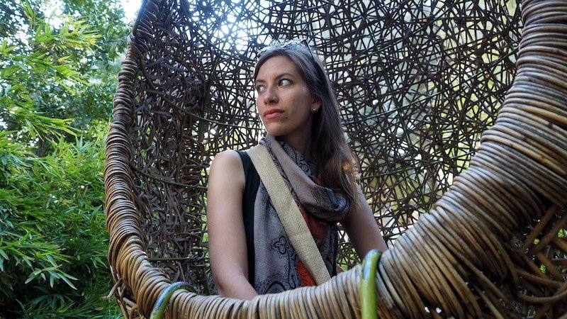 Audrey Bergner of That Backpacker relaxing in a woven hanging chair surrounded by lush greenery at a serene garden spot in Cape Town, enjoying a peaceful break during sightseeing