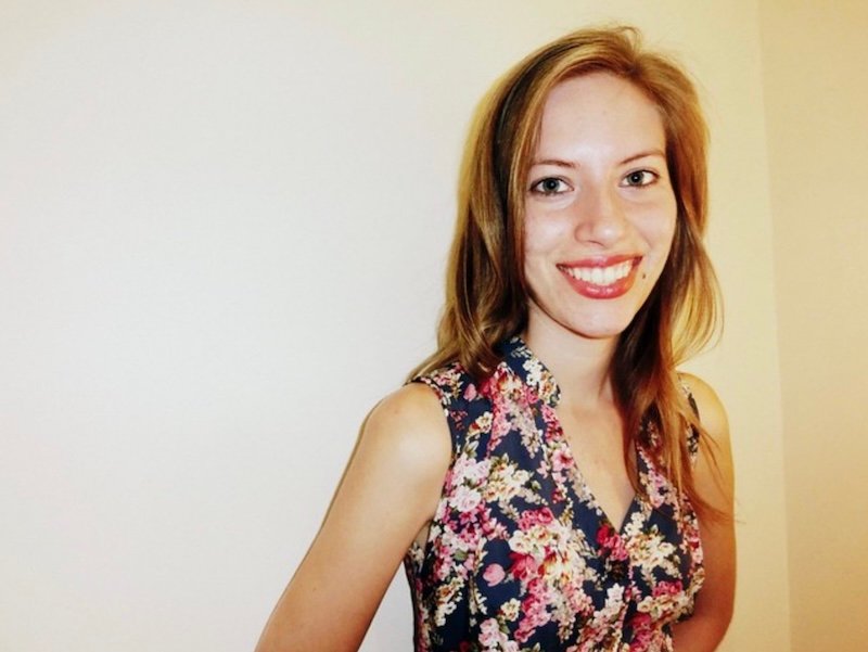 That Backpacker Audrey Bergner smiling indoors in Hanoi, Vietnam, wearing a newly purchased sleeveless floral dress from a local tailor shop, showcasing her look book of custom-made clothing while highlighting the city’s vibrant fashion scene during her month-long Vietnam travel itinerary
