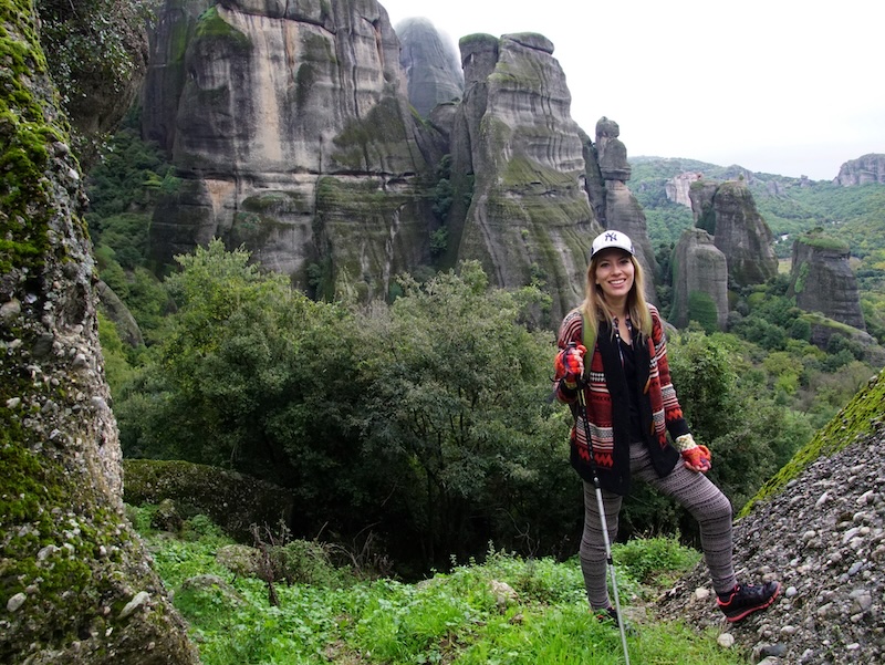 That Backpacker Audrey Bergner hiking with pole in hand in Meteora, Greece wearing an ear to ear big smile 