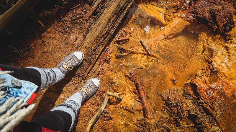 Audrey Bergner from That Backpacker standing on the vibrant orange-red iron-rich earth at the Paint Pots in Kootenay National Park, where mineral deposits stain the ground in striking hues during our Canadian Rockies road trip