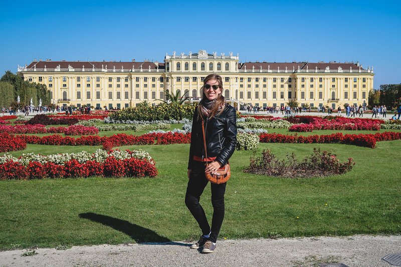 That Backpacker Audrey Bergner standing in front of the grand yellow façade and vibrant flower gardens of Schönbrunn Palace in Vienna, Austria, on a sunny day That Backpacker Audrey Bergner standing in front of the grand yellow façade and vibrant flower gardens of Schönbrunn Palace in Vienna, Austria, on a sunny day
