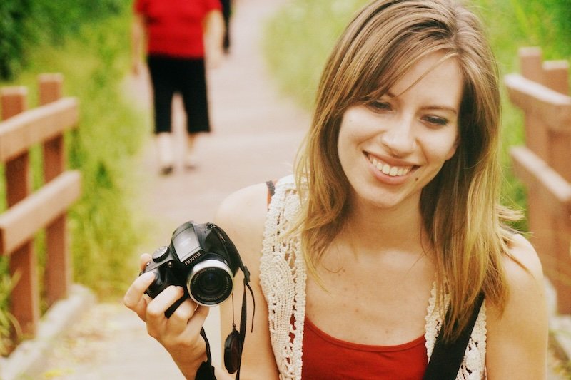 That Backpacker Audrey Bergner smiling with camera in hand while exploring a scenic walkway in South Korea – travel blogger photography moment