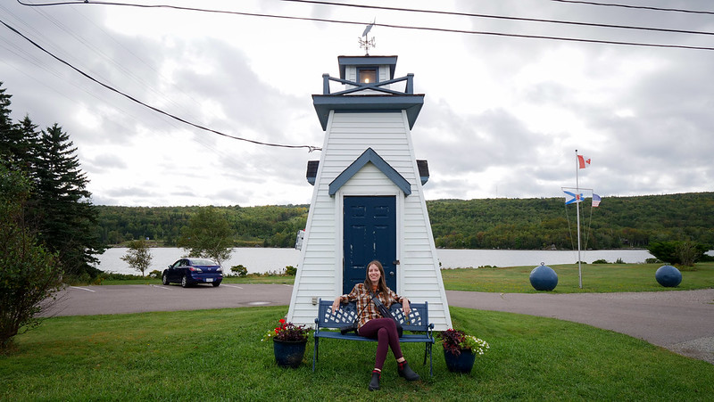 The Cove Restaurant at Aulds Cove with a mini lighthouse entrance and bench with That Backpacker Audrey Berger relaxing and lounging