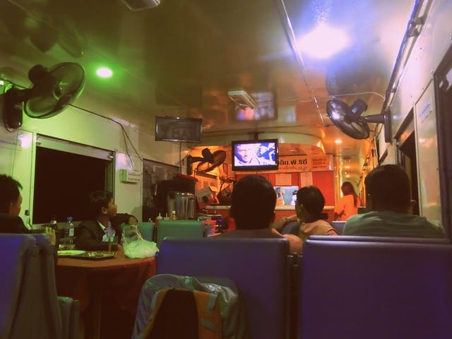 The dining cart on the train ride in Thailand with fans blowing and entrainment being shown on the screen