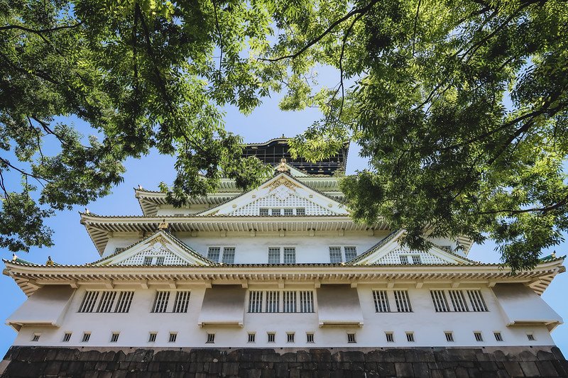 The first stop of our trip to Osaka was Osaka Castle from a creative low angle vantage point framed by trees in Japan