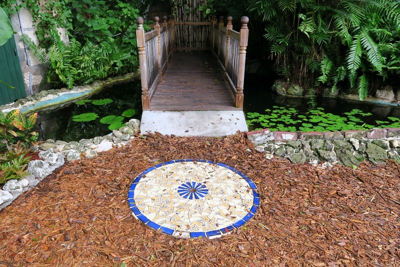 The gardens in Ernest Hemingway's home in the Florida Keys with lush greenery and walking bridge up ahead 