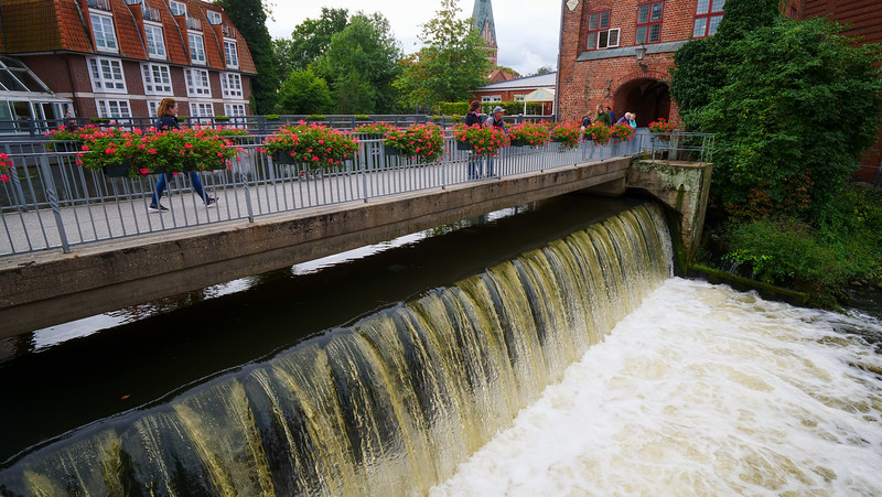 The Ilmenau River flowing through Lüneburg's old town with a pedestrian bridge crossing in Germany