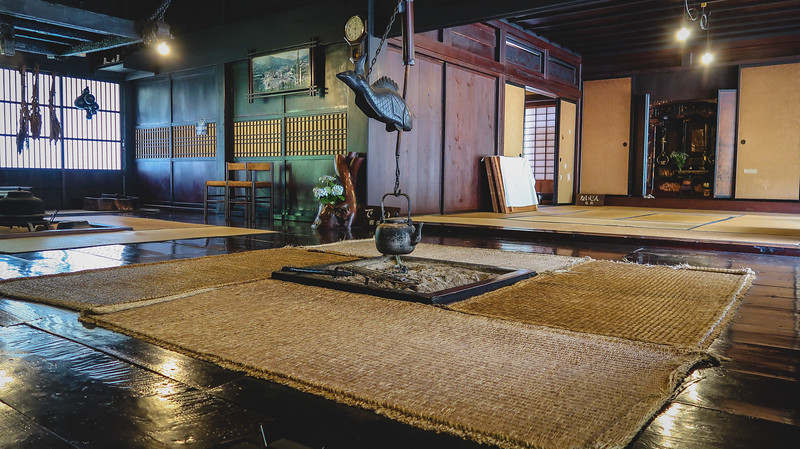 The interior of a farmhouse in Shirakawa-go with a traditional floor mat and a fish structure holding up the tea pot in the middle The interior of a farmhouse in Shirakawa-go with a traditional floor mat and a fish structure holding up the tea pot in the middle