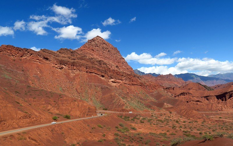 The landscapes on the road to Cafayate, Argentina with a small amount of traffic on the road and giant mountains dominating 