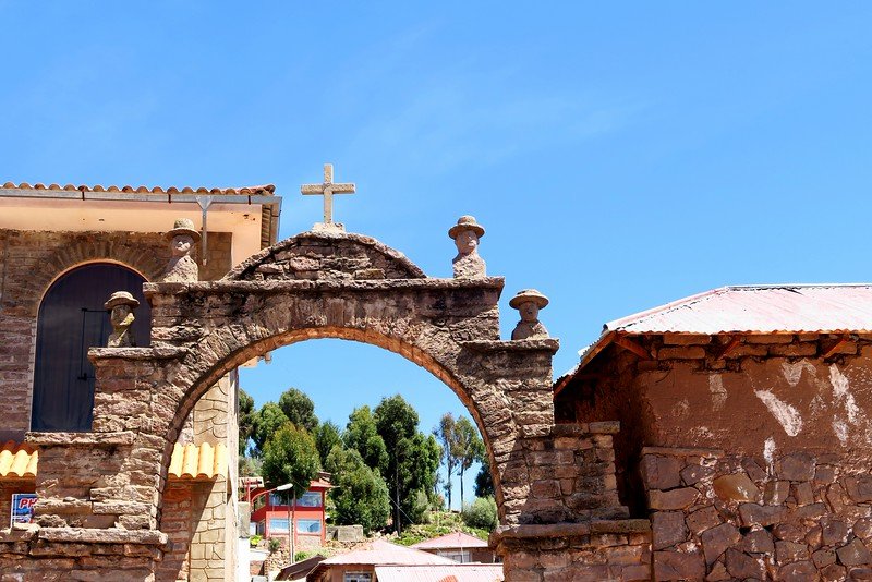 The town square of Taquile featuring a rustic archway with cross at the top and carvings along its side on Lake Titicaca, Peru 