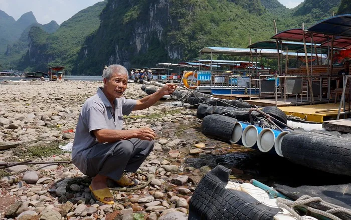 This local man perfectly positioned himself in my frame kneeled down by the river boats going down the Li River in China