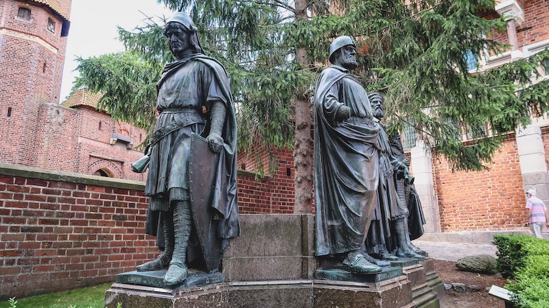 Three distinct statues on the grounds of Malbork Castle in Poland 