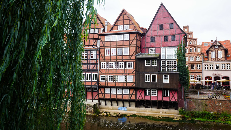 Timber frame architecture with distinct red and orange buildings on the banks of the Ilmenau River in Lüneburg, Germany