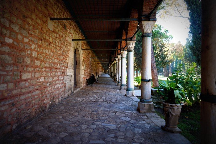 Stone colonnade walkway lined with arches and lush gardens inside Topkapi Palace in Istanbul, Turkey, showcasing the palace’s serene royal grounds and Ottoman architectural elegance